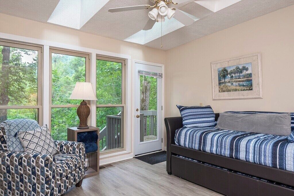 Una habitación con una cama, una silla, una lámpara y un cuadro en la pared.