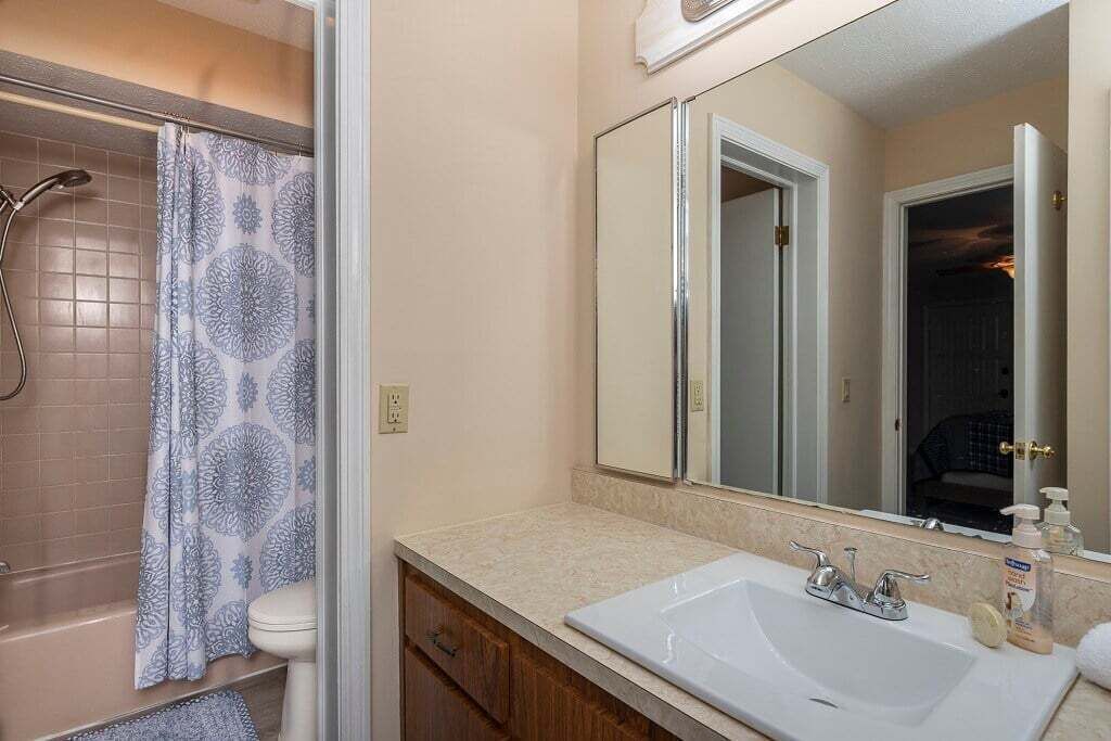 A bathroom with a bathtub, toilet, sink, and mirror.