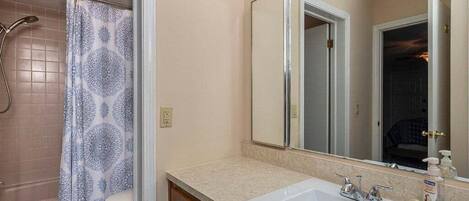 A bathroom with a bathtub, toilet, sink, and mirror.