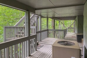 A covered outdoor deck with wooden railings and a central air conditioning unit.