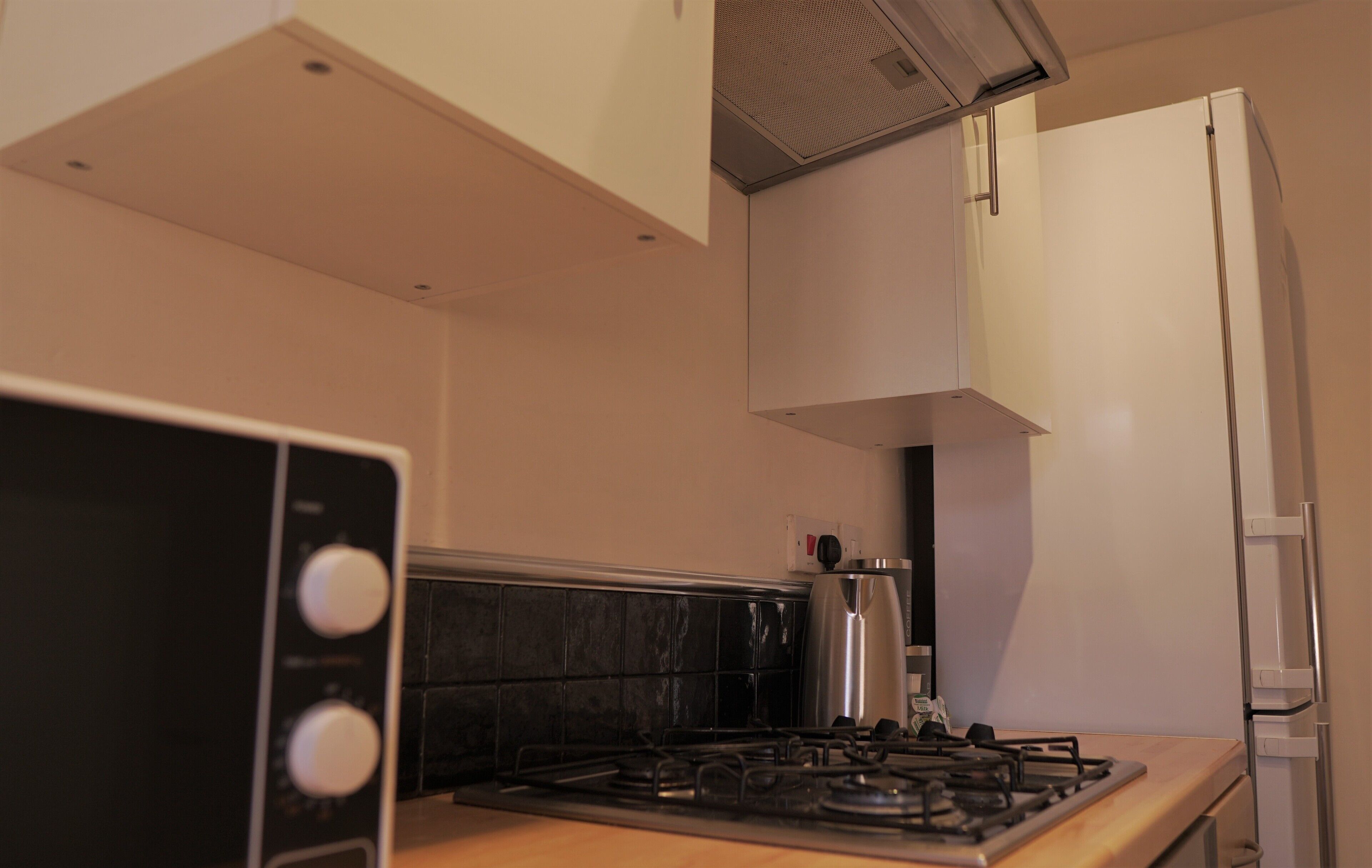 A kitchen with a gas stove, a coffee maker, and a refrigerator.