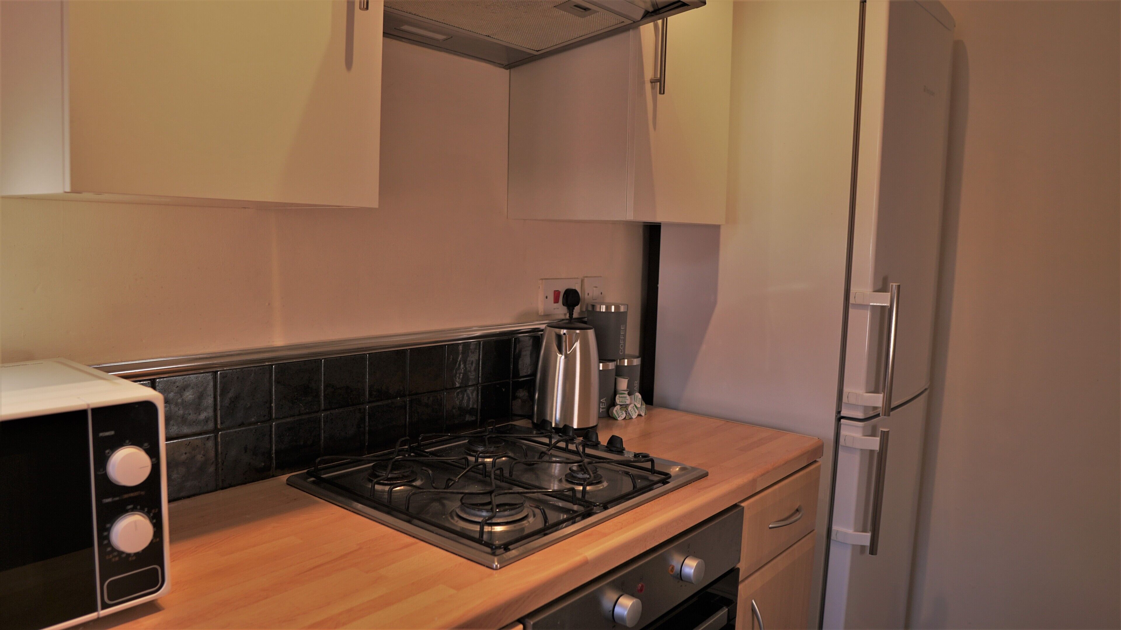 A kitchen with a stove, coffee maker, and refrigerator.