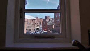 A window view of a street with brick buildings, a red car, and a tower-like structure. - Meadow Terrace (Shrewsbury)