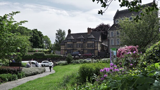 A historic building with a traditional architectural style, surrounded by well-maintained gardens and a paved pathway. - Meadow Terrace (Shrewsbury)