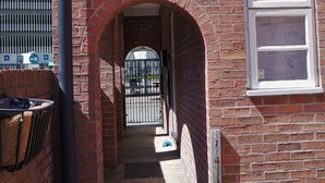 A narrow brick alleyway with a metal gate and a window on the right. - Meadow Terrace (Shrewsbury)