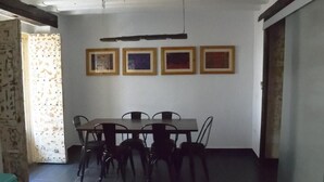 A dining area with a table and chairs, a wall with framed pictures, and a door with a curtain. - Apartment (Cádiz)