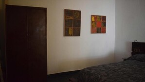A bedroom with a bed, a wardrobe, and two wall-mounted artworks. - Apartment (Cádiz)