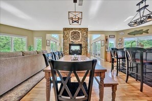 Uma sala de jantar com lareira de pedra, mesa de madeira e cadeiras.