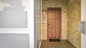 Una entrada moderna con puerta de madera, puerta de cristal y pared de textura de piedra.