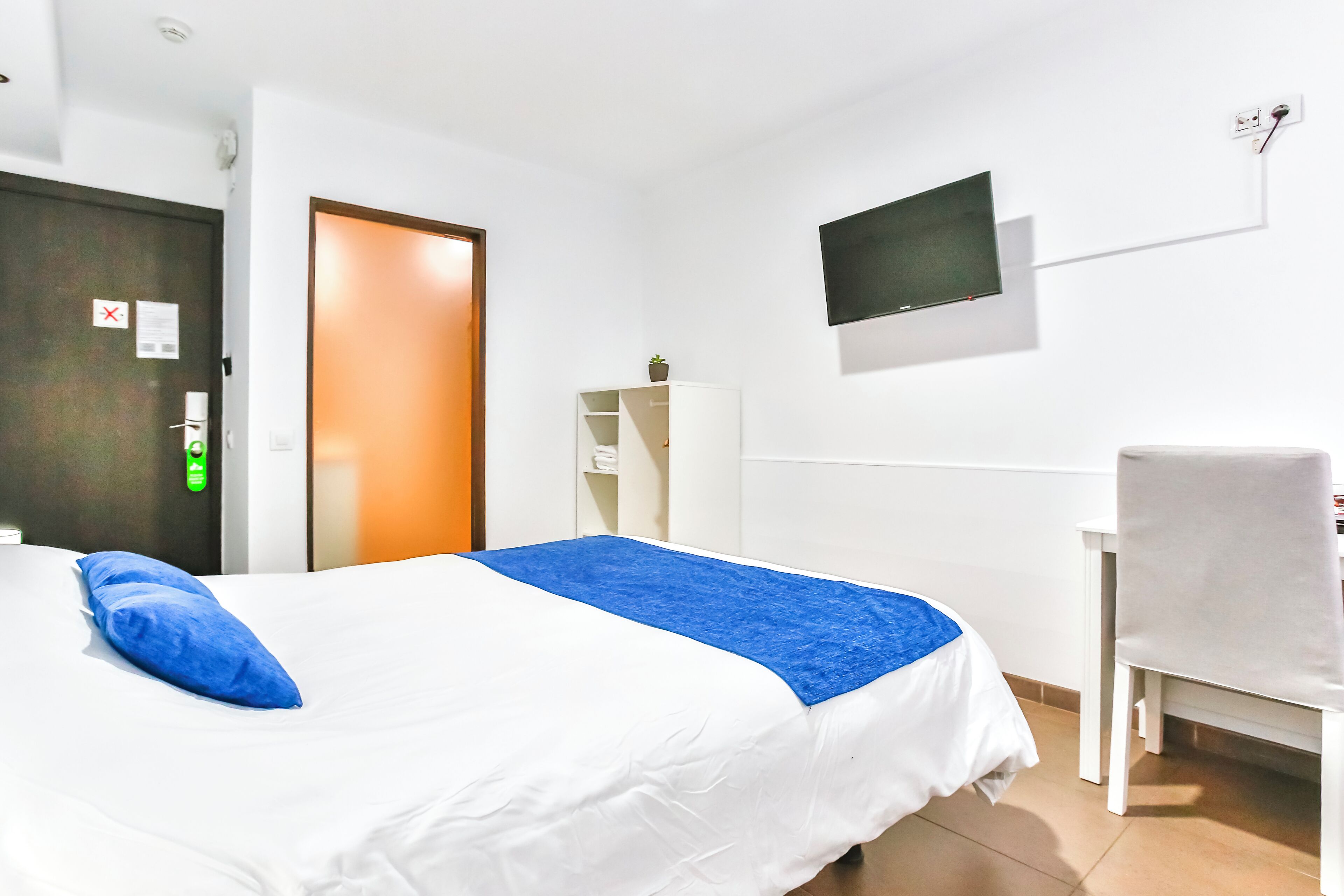 Une chambre d’hôtel avec un lit, un bureau et une chaise.