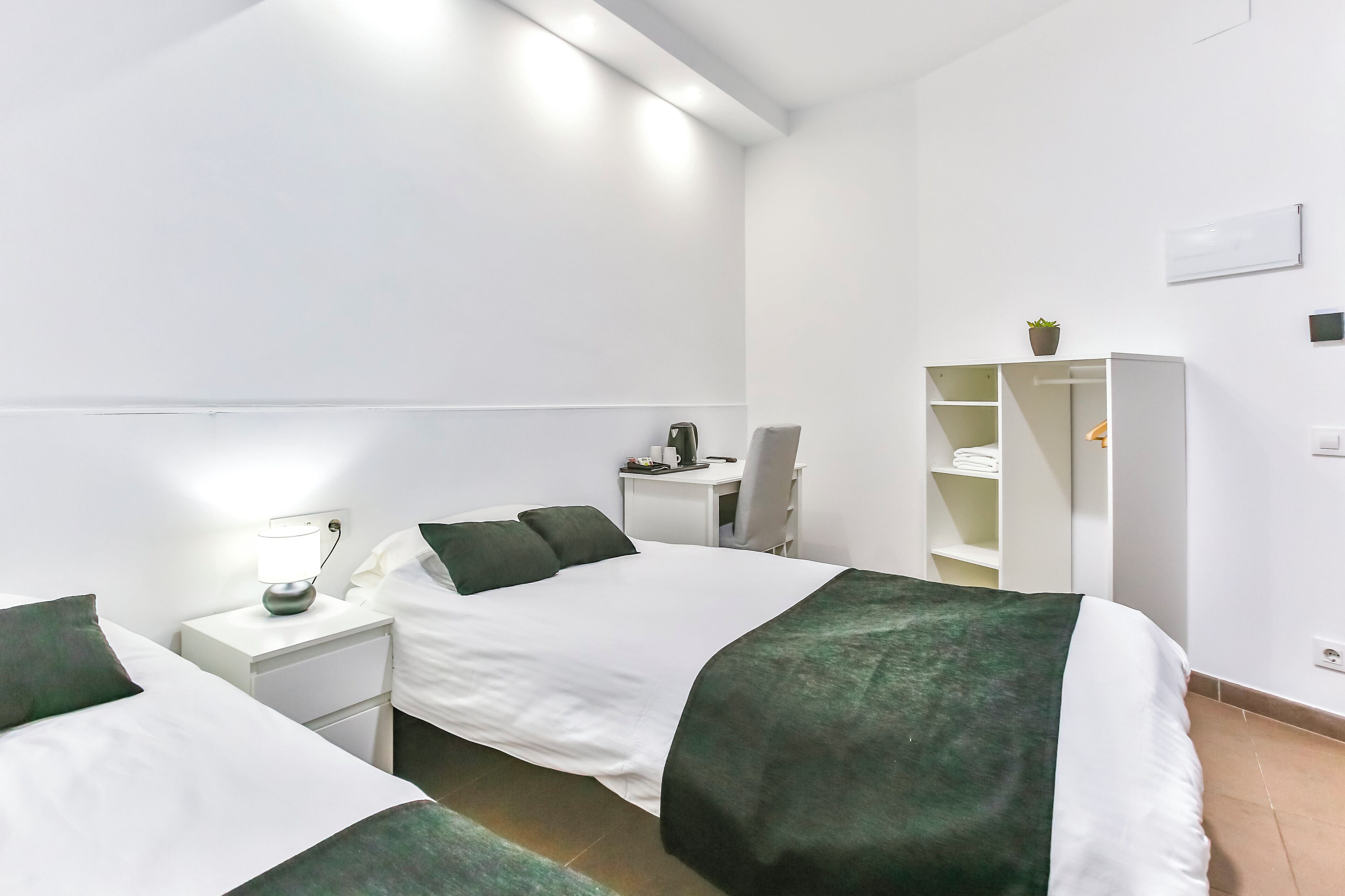 Een moderne hotelkamer met twee bedden, een bureau en een kledingkast.