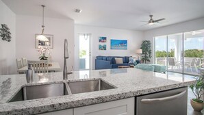 Una cocina moderna con encimera de granito, pileta de acero inoxidable y ventilador de techo.