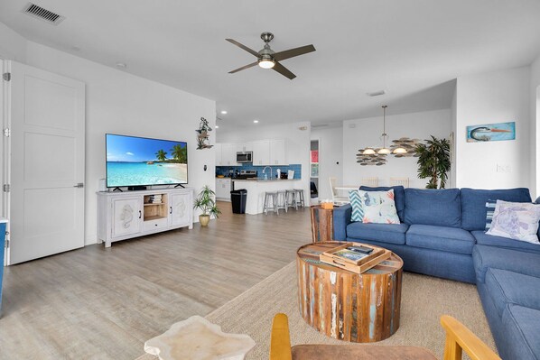 A modern living room with a flat-screen TV, a blue sofa, and a wooden coffee table.
