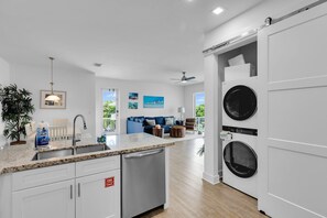 Una cocina moderna con lavavajillas integrado, una isla grande con pileta y una lavadora de pared.