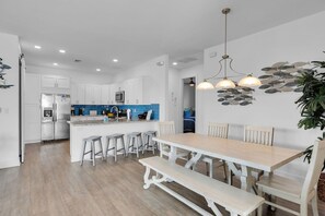 A modern kitchen with white cabinets, a blue backsplash, and a central island with bar stools.