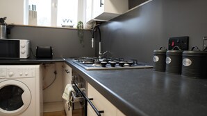 Una cocina moderna con estufa, microondas y cafeteras.