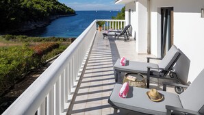A balcony with a view of the sea, a white railing, and two lounge chairs with towels.