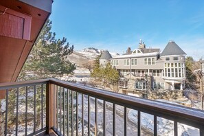 A large house with a balcony, surrounded by snow-covered landscape and trees.