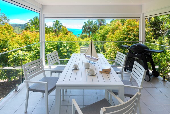 A balcony with a white table and chairs, a sailboat model, and a scooter. - Oasis 13, Oasis 13 on Hamilton Island (Hamilton Island)