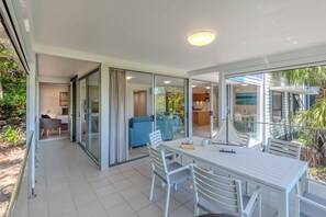 A modern, open-plan living area with a dining table, chairs, and a sofa. - Oasis 13, Oasis 13 on Hamilton Island (Hamilton Island)