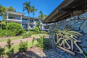 A modern building with a stone wall and a sign that reads "Coast in Hamilton Two." - Oasis 13, Oasis 13 on Hamilton Island (Hamilton Island)