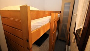 A small, narrow room with a wooden bunk bed, a small cabinet, and a door with a curtain. - Sea view cabin studio i (Saint-Cyprien)