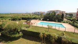 A swimming pool surrounded by greenery, with buildings in the background. - Sea view cabin studio i (Saint-Cyprien)