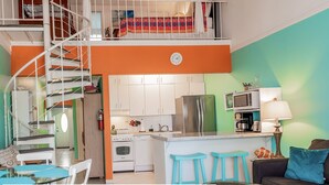 A multi-level apartment with a kitchen, dining area, and a staircase.