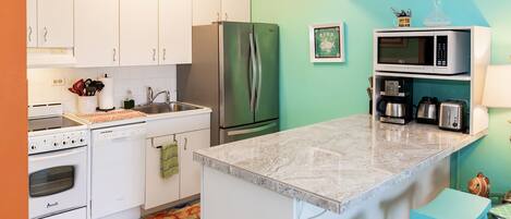 A modern kitchen with white cabinets, a stainless steel refrigerator, a microwave, a coffee maker, and a toaster.