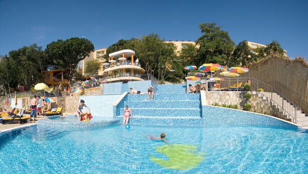 Piscina com degraus de acesso, cercada por espreguiçadeiras e guarda-sóis.