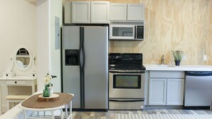 A modern kitchen with a refrigerator, microwave, oven, dishwasher, and a dining area with a table and chairs. - Romantic Private Space for Couple's Getaway w/Hot Tub (Buena Vista)