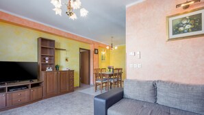 Una sala de estar con sofá, televisor, mueble de madera y un comedor con sillas y mesa.