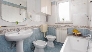 Un baño con lavamanos, bidé, inodoro y bañera.