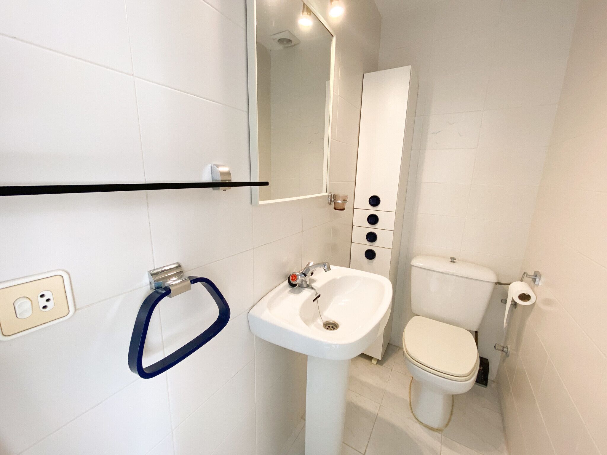 Un baño con lavamanos blanco, inodoro y espejo.