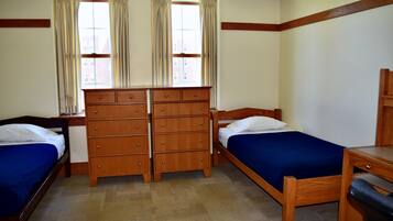 A room with two wooden beds, a wooden dresser, and a desk.