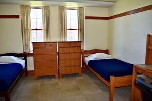 A room with two wooden beds, a wooden dresser, and a desk. - Acadia University (Wolfville)