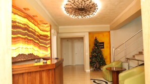 Zona de recepción con mostrador de madera, un árbol de Navidad y una escalera.
