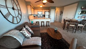 A living room with a sofa, a coffee table, and a dining area with chairs. - SBC #106 Oceanfront - Hear the Ocean, Steps to the Promenade and Beach Access (Seaside)