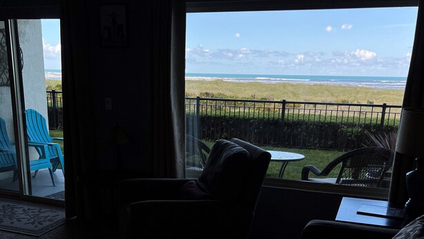 A room with a view of the ocean, a patio area with chairs, and a small table. - SBC #106 Oceanfront - Hear the Ocean, Steps to the Promenade and Beach Access (Seaside)