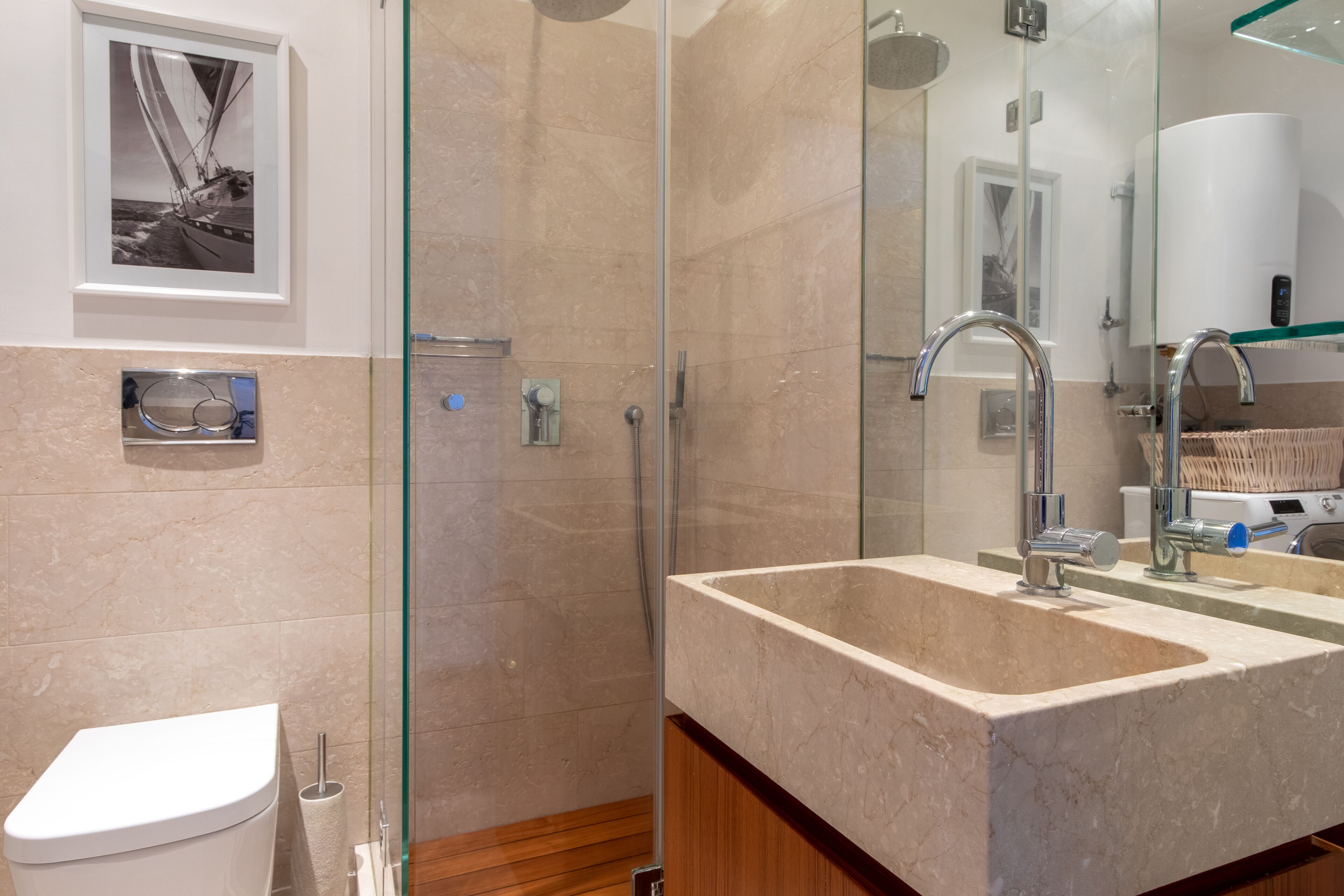 A modern bathroom with a glass shower enclosure, a marble sink, and a toilet.