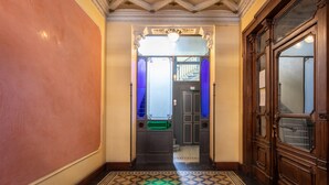 A hallway with ornate ceiling, a green trash bin, and a wooden door with a window. - Porta Venezia-Design apartment, 2-bedrooms, Netflix, wifi (Milano)