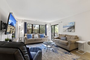 En moderne stue med to sofaer, et sofabord og et fladskærms-tv.