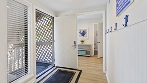 Un corridoio con una porta che dà su un balcone, una mensola a parete con oggetti decorativi e un'opera d'arte incorniciata.