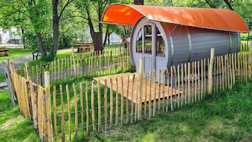 A small, rustic cabin with a wooden fence and a wooden deck.