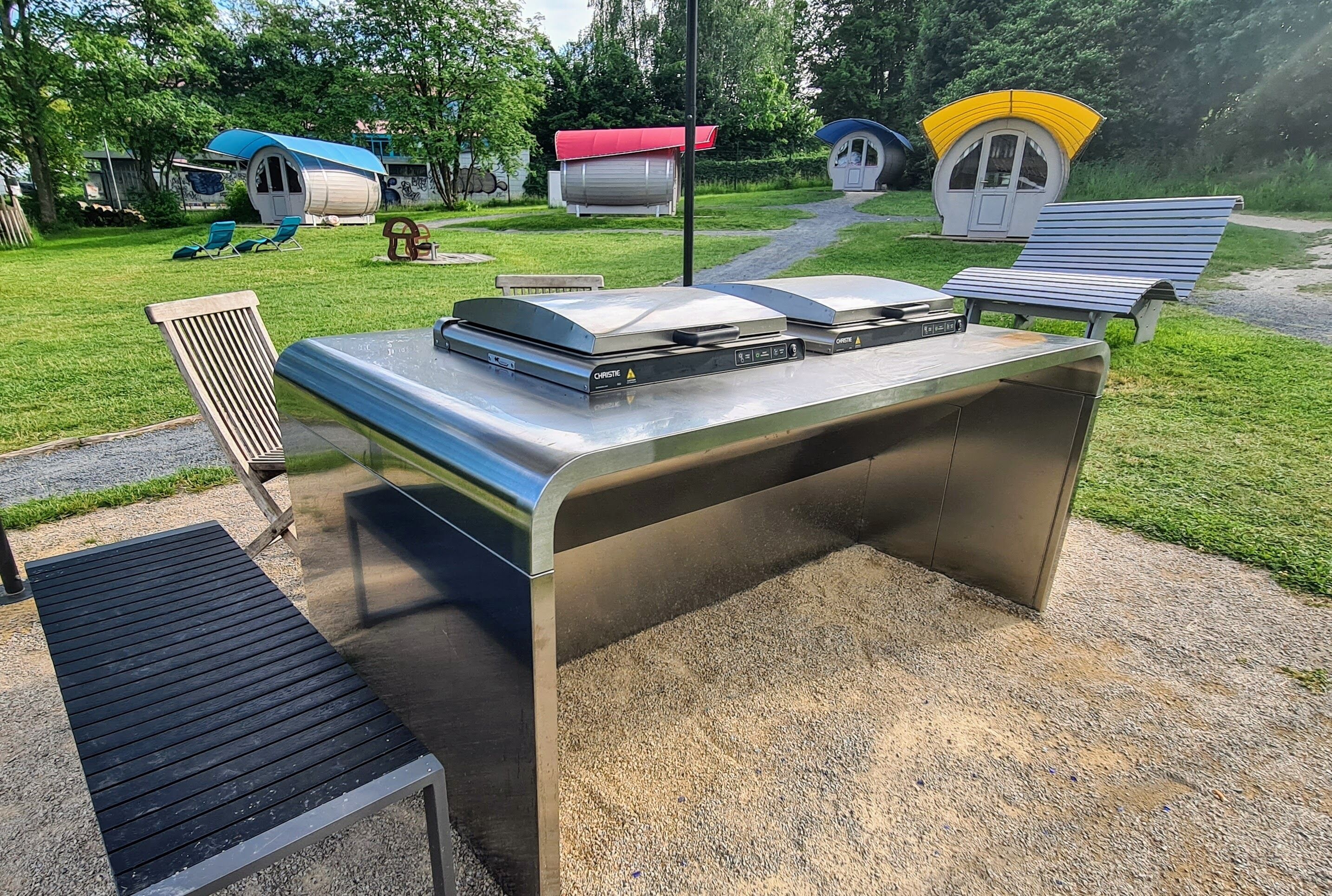 A patio area with a metal table, two lounge chairs, and a small grill station.