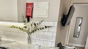 Eine Küche mit Marmorarbeitsplatte, einer Kaffeetasse, einem Teller mit Croissants und einer Vase mit Grünpflanzen.