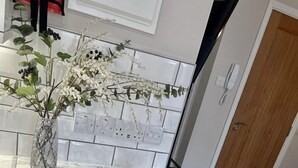 Eine Küche mit Marmorarbeitsplatte, zwei weißen Tassen, einem Teller mit einem Croissant und einer Vase mit weißen Blumen.