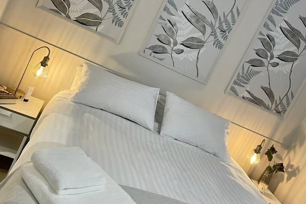 A neatly made bed with white linens and a folded towel, flanked by two bedside tables with lamps.