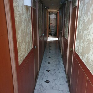 A narrow hallway with patterned wallpaper and a tiled floor. - Isak Minitel (Seoul)