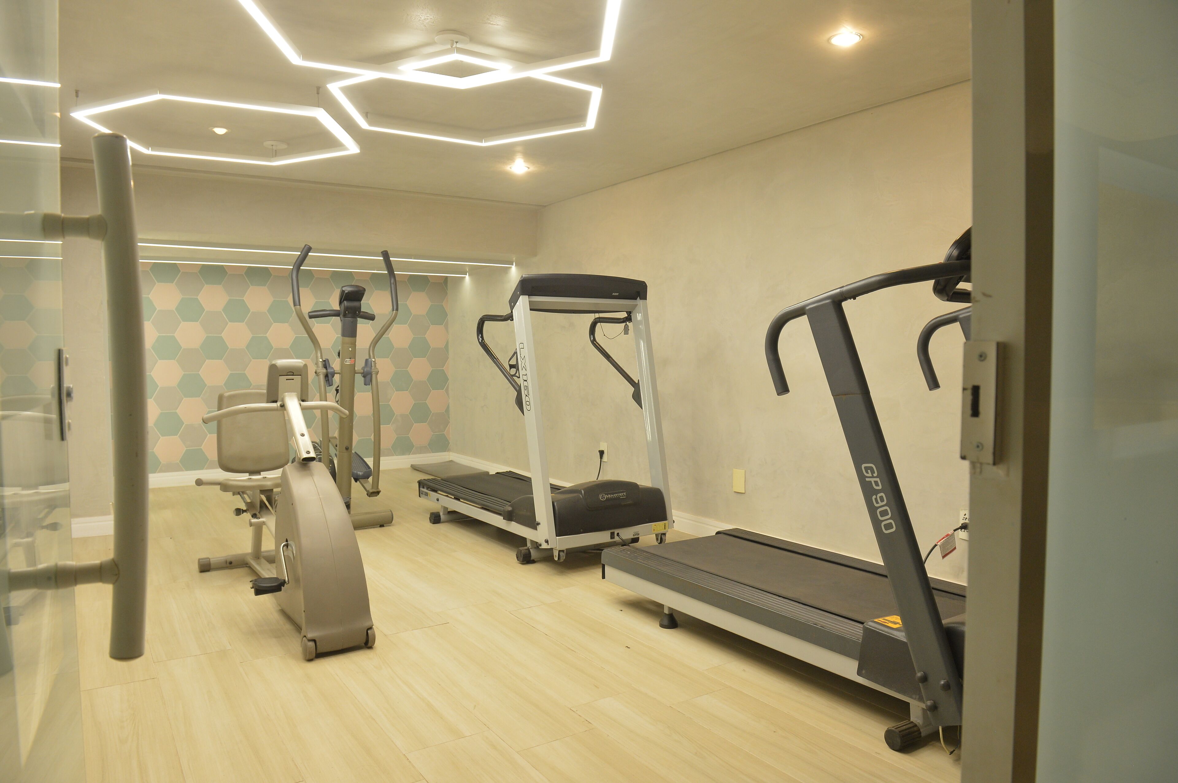 Un gimnasio con máquinas de cardio, una cinta de correr y una elíptica.